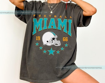 May include: A charcoal gray t-shirt with a vintage-style graphic of a football helmet and the text "FOOTBALL MIAMI 19 66".