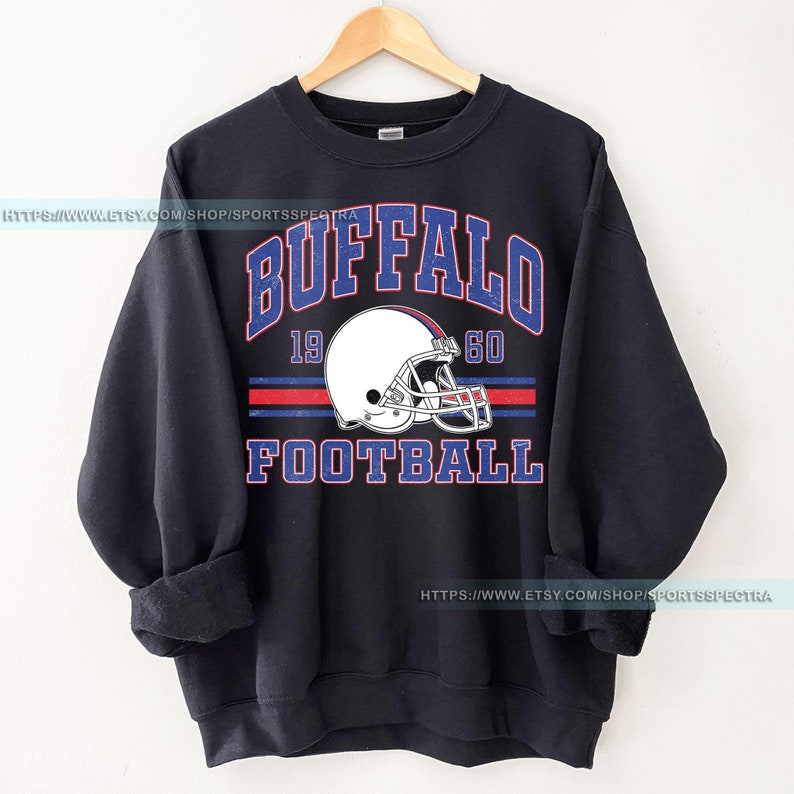 Może przedstawiać: Czarna bluza z nadrukiem w stylu vintage przedstawiającym kask do futbolu amerykańskiego i tekst "BUFFALO FOOTBALL 1960".