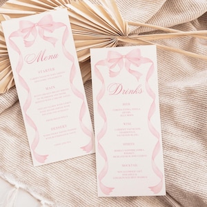 Op de afbeelding: Twee lichtroze trouwmenukaarten met roze lintaccenten en tekst. Eén kaart zegt "Menu" met secties "Voorgerecht", "Hoofdgerecht" en "Dessert". De andere kaart zegt "Dranken" met secties voor "Bier", "Wijn", "Sterke drank" en "Cocktail".