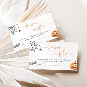 Op de afbeelding: Twee witte Halloween-luierloterijkaarten. Elke kaart heeft een illustratie van een spinnenweb, vleermuis en pompoen. De tekst luidt "diaper raffle" in een stijlvol lettertype, met instructies eronder.