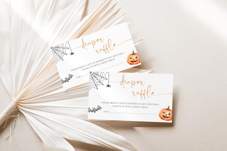 Op de afbeelding: Twee witte Halloween-luierloterijkaarten. Elke kaart heeft een illustratie van een spinnenweb, vleermuis en pompoen. De tekst luidt "diaper raffle" in een stijlvol lettertype, met instructies eronder.