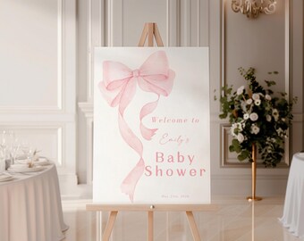 May include: A white welcome sign with a pink watercolour bow and the text "Welcome to Emily's Baby Shower May 21st, 2024".