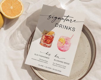 May include: A white card with the words "Signature Drinks" and two watercolor cocktail illustrations. The "Old Fashioned" cocktail is in a rocks glass, and the "Blushing Bride" is in a stemless glass. The card includes drink ingredients and a wedding date.