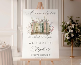 May include: A white sign on a wooden easel with the text "A new chapter is about to begin" and "Welcome to Sophie's Bridal Shower". The sign features a watercolour illustration of books and flowers. The date is September 21st, 2016.