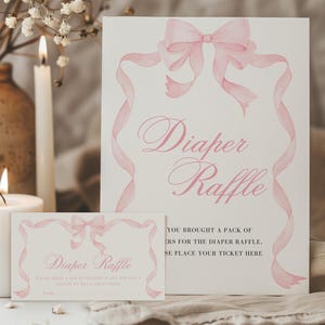 K&ouml;nnte beinhalten: Zwei Karten mit dem Text "Diaper Raffle" in rosa Schrift. Die Karten haben ein Aquarell-Schleifen- und Banddesign in Rosa. Eine brennende Kerze und eine Vase mit Blumen befinden sich im Hintergrund.
