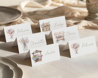 May include: White place cards with watercolor floral illustrations and names like Patricia, Evelyn, and Claire. The cards feature bouquets, flower carts, and mason jars filled with flowers. Ideal for weddings or events.