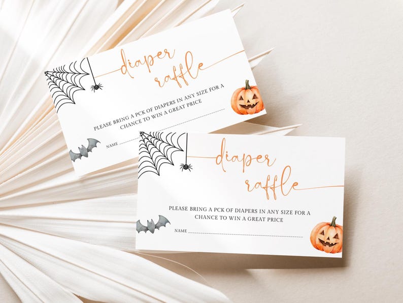 Op de afbeelding: Twee witte Halloween-luierloterijkaarten. Elke kaart heeft een aquarel pompoen, spinnenwebben, vleermuizen en de woorden "diaper raffle" in gouden script. De kaarten bevatten ruimte voor een naam en instructies.