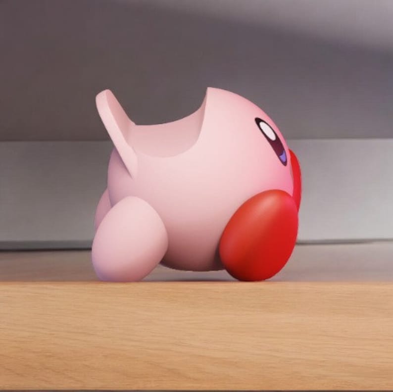May include: A pink and red character figurine with a rounded shape and a large, open mouth. The figurine is made of plastic and has a smooth, glossy finish.