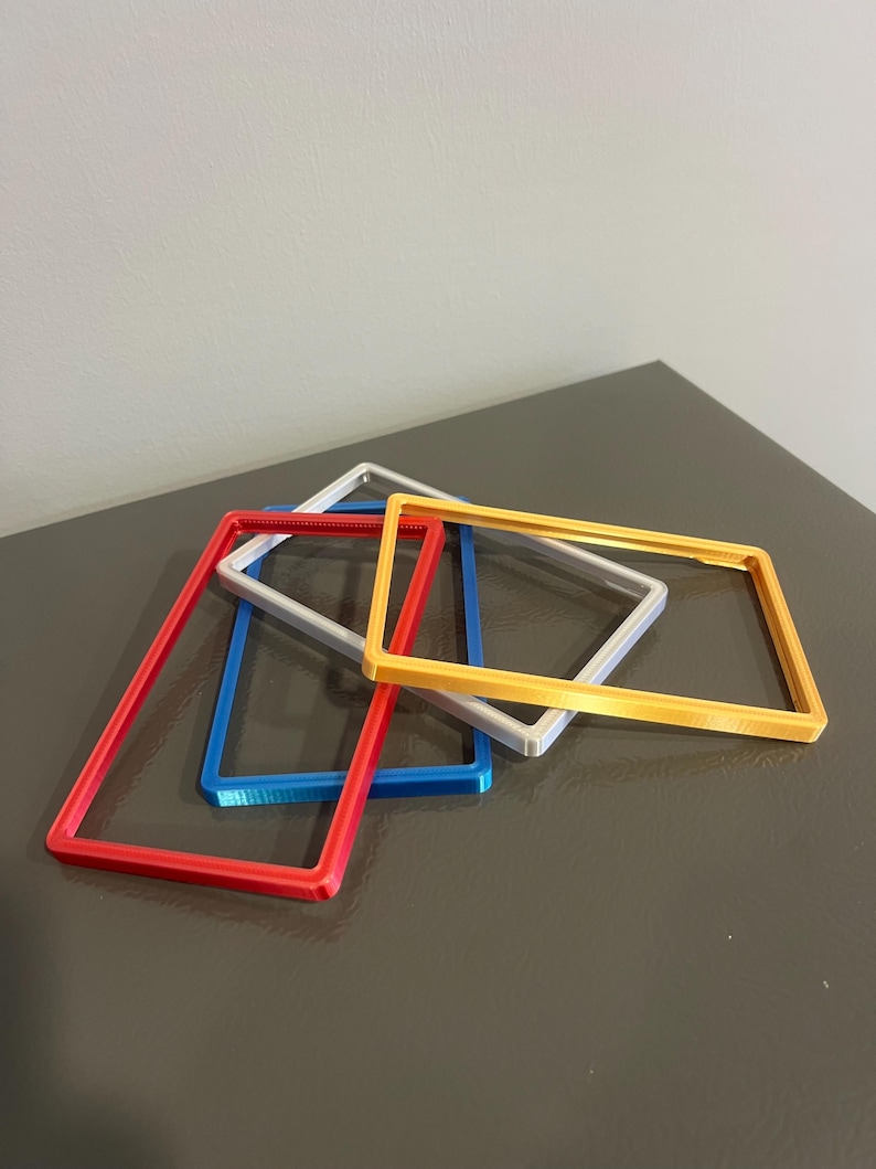 May include: A collection of rectangular frames in red, blue, silver, and yellow. The frames are stacked and slightly overlapping, showcasing their vibrant colors and simple design. The frames appear to be made of plastic or a similar material.
