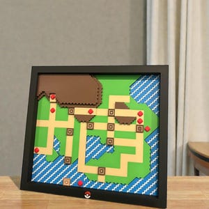 May include: Framed map art featuring a pixelated design with green, brown, and blue elements. The map is set against a black frame and includes red accents. A Pok&eacute; Ball is visible at the bottom.