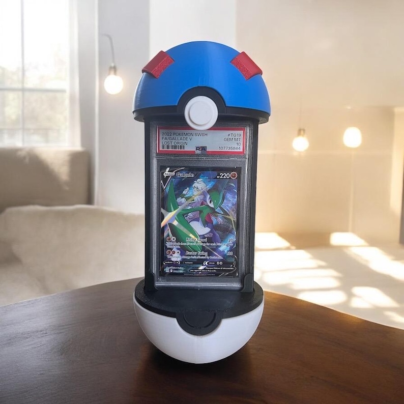 Op de afbeelding: Een blauw, wit en zwart display in de vorm van een Pok&eacute; Ball, met een Pok&eacute;mon-verzamelkaart. De kaart zit in een beschermhoes en heeft een groen en wit personage. De tekst op de kaart luidt "2022 Pokemon SWSH FAISALLADE V LOST ORIGIN".