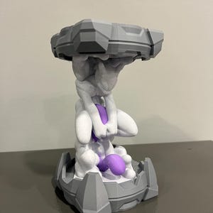 May include: A 3D-printed sculpture featuring a figure supporting a platform. The sculpture is primarily gray and white, with a vibrant purple accent. The design has a geometric and stylized aesthetic, suitable for home decor.