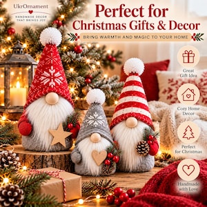 May include: Three plush gnomes with long white beards and tall pointed hats. The left gnome wears a red hat with white snowflakes, the center a gray hat with a snowflake, and the right a red and white striped hat. Each has a pom-pom.