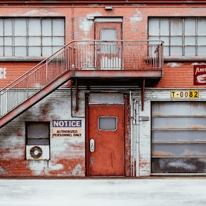 May include: Exterior of a weathered brick building with a red metal staircase and door. The words "SHIPPING OFFICE" are painted on the wall. A sign for "Anheuser-Busch Beer" is visible. A sign reads "NOTICE AUTHORIZED PERSONNEL ONLY".
