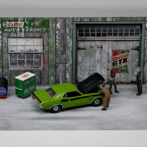 Könnte beinhalten: Ein Diorama einer klassischen Autowerkstatt mit einem grünen Muscle-Car. Die Werkstatt hat eine verwitterte Holzfassade mit der Aufschrift "Castrol Auto Service". Miniaturfiguren sind um das Auto herum positioniert, die Motorhaube ist geöffnet.