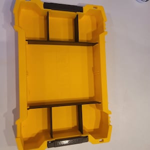 May include: A yellow plastic storage box with black dividers. The box has the text "TOUGH SYSTEM" printed on the front.