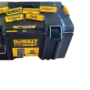 Könnte beinhalten: Eine schwarze und gelbe DeWalt ToughSystem 2.0 Werkzeugbox mit verschiedenen gelben Etiketten, die am Deckel befestigt sind. Die Etiketten beinhalten: Hochdruckreiniger, DeWalt, Säbelsäge, Schlagwerkzeug, Schwingschleifer und Bohrmaschine.