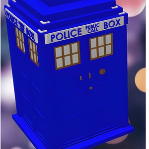 Op de afbeelding: Een blauwe politiekiosk met een wit bord waarop "Police Public Call Box" staat. De kiosk heeft een kleine, gele antenne bovenop en een paar ramen met bruine kozijnen.