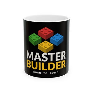 Peut inclure: Un mug en céramique noir orné d'un motif représentant quatre briques de construction en plastique rouge, vert, bleu et jaune. Le texte MASTER BUILDER est imprimé en grandes lettres blanches et jaunes, avec BORN TO BUILD en dessous en blanc.
