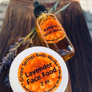 May include: A white jar with a yellow and orange label that reads "Green Springs Body Works Lavender Face Food 2 oz www.greensprings0.etsy.com 541 482-0857". A clear glass bottle with a dropper and a yellow and orange label that reads "Green Springs Body Nature's Facial Serum greensprings0.etsy.com" is next to the jar.