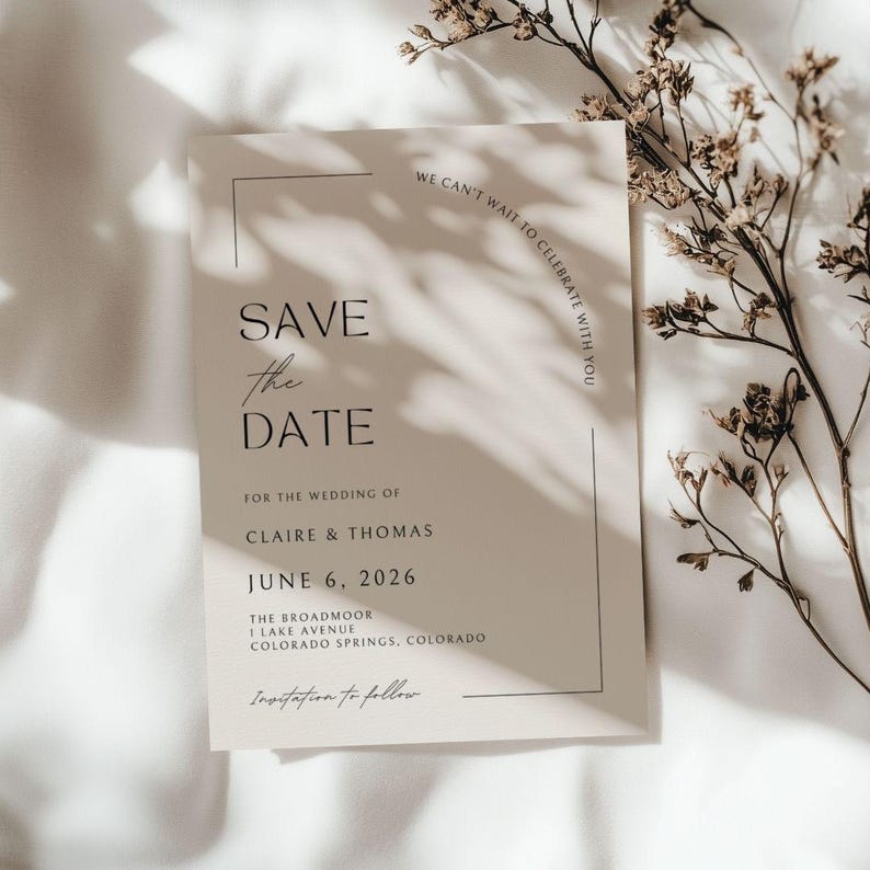 Plain, bright white, sheet background with shadows a sprig of a dried tree branch  - it gives boho, nature vibe without too much clutter. In the center of the mock up is a plain white wedding save the date card - it has elegant, cursive scripts. This card has a few different fonts that actually make up the border in an unique, modern style. The card itself if black and white.