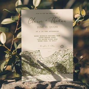 May include: Wedding invitation with a mountain landscape illustration in green ink on a cream-colored card. The text reads "Join us for the wedding of Claire + Thomas, June 6, 2026, at 4 in the afternoon, Rocky Mountain National Park, Aspen Meadow Lodge."