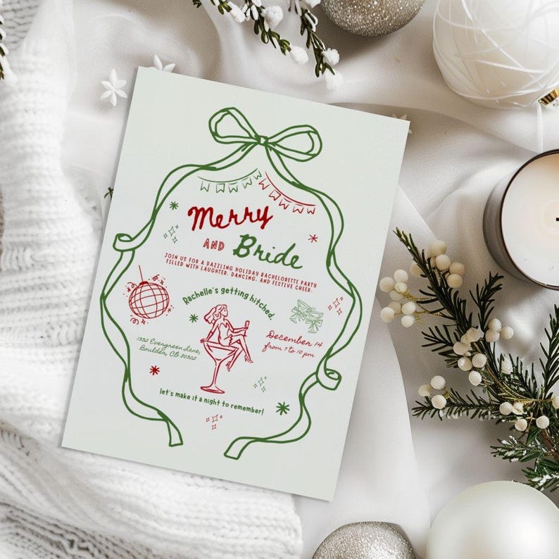 This is a mock up photo of Christmas table with snowy branches, white knit sweater, and white candles. In the center is a Bachelorette party invitation.