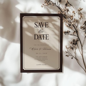 May include: A formal wedding invitation with a dark brown border and a cream-colored background. The text "SAVE the DATE" is prominently displayed, along with the names Claire & Thomas and the date 06.21.2028. The invitation includes the venue address.