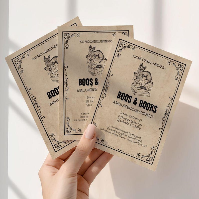 This is a lifestyle image of a womens hand holding three of the Halloween Party Invitations.
