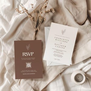 May include: Wedding stationery set with a brown RSVP card and a cream invitation. The invitation features the names Charlotte Williams and Matthew Carter. Both cards have a floral design and are on a neutral fabric background.