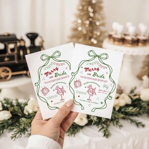This is a lifestyle image of a Christmas, holiday table featuring florals, lights, a tree and ornaments. In the foreground is a women's hand holding two Christmas themed Bachelorette invites - there is a large doodle of a women in a cocktail glass, hand drawn green bow as the border of the card.