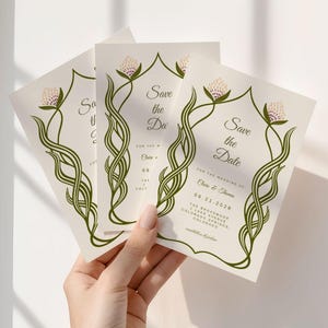 Three ivory-colored "Save the Date" cards with elegant green script. The cards feature the text "save the date", names, and a date. The cards are held in a hand, with the text "Eliane & Thomas" and the date, the border is in green vines.