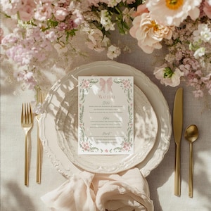 May include: A formal table setting with a menu card, plates, and gold cutlery. The menu card features a pink bow and floral design. The table is decorated with pink flowers and a linen napkin. The overall theme is elegant and romantic.