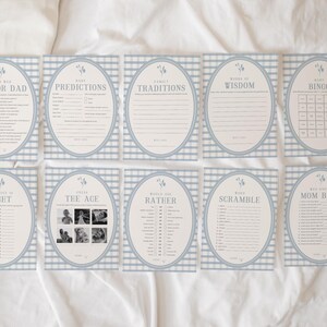 Op de afbeelding: Een set van tien familiespelkaarten met een lichtblauwe gingham-patroonrand. Elke kaart heeft een andere speltitel, zoals "Mama of Papa", "Voorspellingen" en "Bingo". De kaarten zijn gerangschikt op een wit oppervlak.