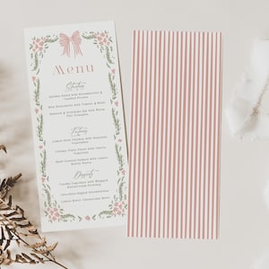 May include: A wedding menu card with a floral and bow design, featuring a menu of starters, entrees, and desserts. A second card with pink and white vertical stripes is next to it. White ribbon and a spool are also in the image.