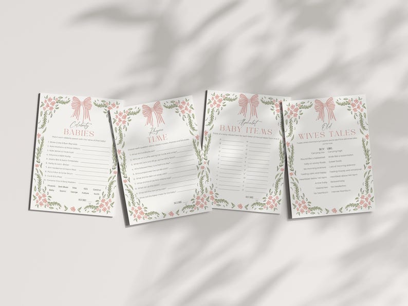 May include: Four baby shower game cards with pink bow and floral designs. The cards include games like "Celebrity Babies," "Guess the Baby Items," and "Old Wives Tales." The cards are on a white surface with shadows.
