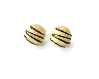 May include: A pair of white chocolate earrings with dark chocolate stripes. The earrings are round and have a smooth, glossy finish.