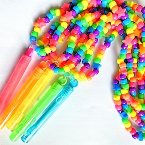 May include: A rainbow colored beaded necklace with star-shaped charms. The necklace is attached to four colorful bubble wands.