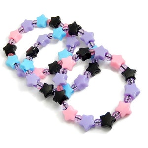 May include: Three star-shaped beaded bracelets in pink, blue and black. The bracelets are made of plastic and have a shiny finish.