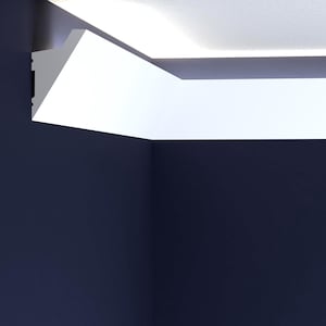 May include: A corner view of a room featuring a white crown molding against a dark blue wall. The molding has a modern, angular design, creating a sharp contrast with the wall. The ceiling is white, and the overall aesthetic is minimalist.