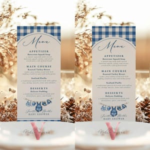 Op de afbeelding: Twee menukaarten voor een babyshower met een blauw en wit geruit patroon bovenaan. Het menu bevat voorgerechten, hoofdgerechten en desserts. De onderkant van de kaart luidt "Janette Herold's BABY SHOWER."