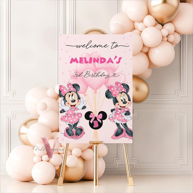 May include: A pink welcome sign for a 3rd birthday party, featuring Minnie Mouse illustrations and heart-shaped balloons. The sign includes the text "welcome to MELINDA'S 3rd Birthday". The sign is displayed on a gold easel, with a balloon arch in the background.