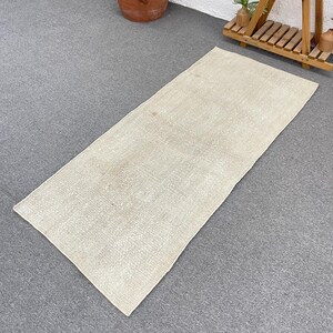 May include: A rectangular area rug featuring a woven texture in a neutral beige color. The rug has a flat-weave construction with subtle variations in the light tan fibers, creating a consistent and uniform appearance across the entire surface.