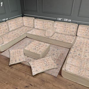 May include: U-shaped sectional sofa with floral patterned cushions and a matching ottoman. The sofa measures 130 inches (330 cm) wide and 75 inches (190 cm) on the shorter side. Includes two throw pillows and a rug with a similar design.