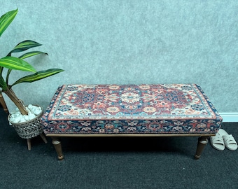 May include: A wooden bench with a dark blue, red and cream patterned cushion. The bench has a traditional design and is perfect for adding a touch of elegance to any room.