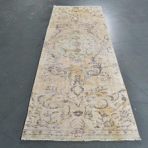 Op de afbeelding: Een vintage-stijl loper met een beige achtergrond en een bloemenpatroon in bruintinten. De loper heeft een verweerde look en is perfect om elke kamer een vleugje traditionele charme te geven.