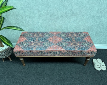 May include: A wooden bench with a patterned fabric cushion. The cushion has a blue, red and white geometric design. The bench has a dark wood frame and legs.