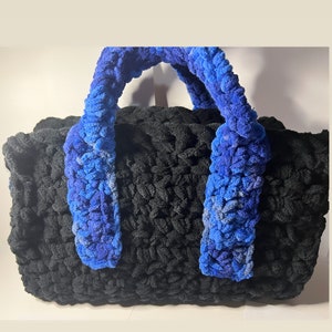 May include: A black crocheted tote bag with blue crocheted handles.