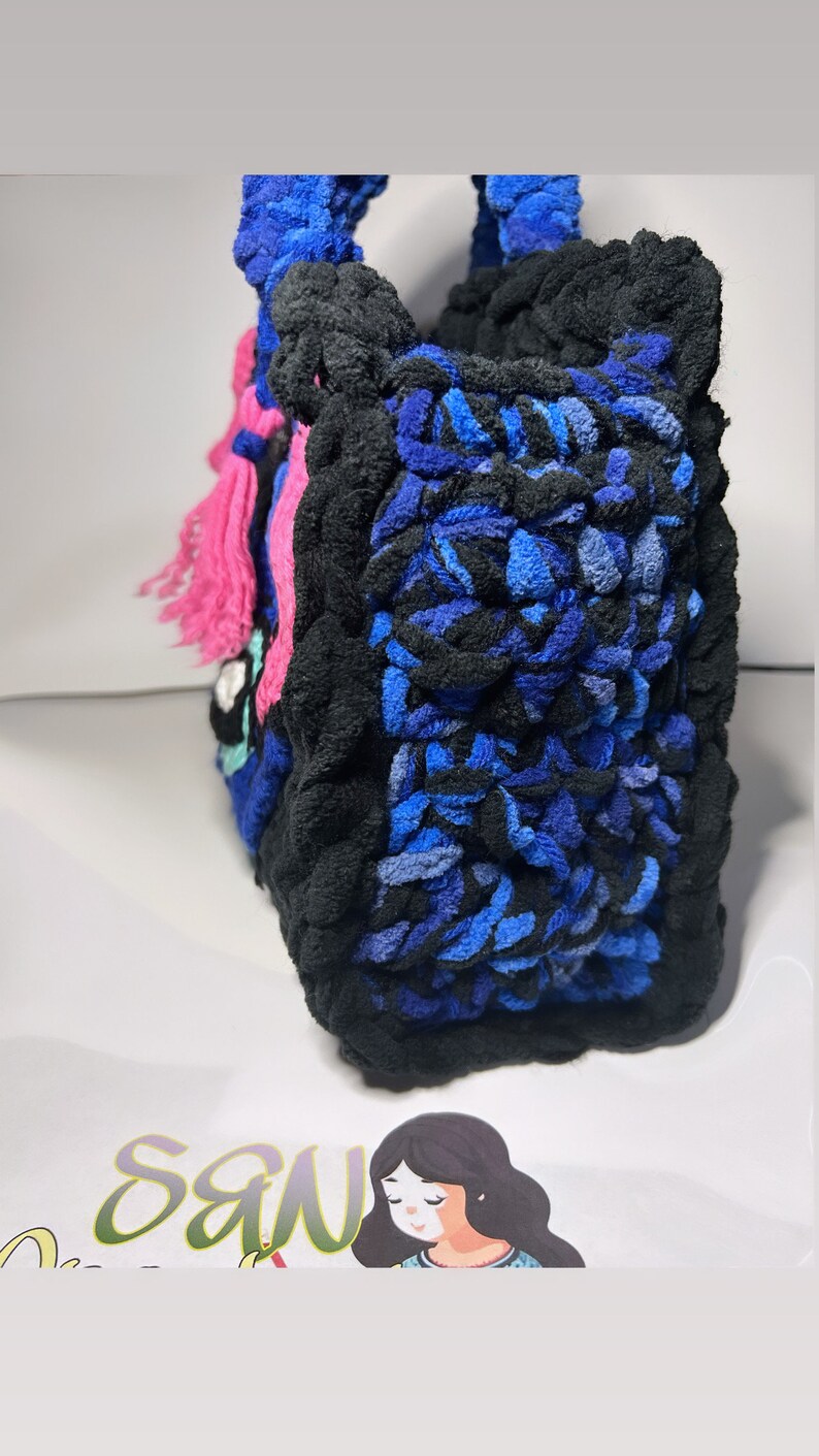 May include: A blue, black, and pink crocheted tote bag with a fringe detail. The bag is made with a thick, textured yarn.