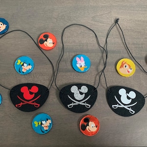 May include: Three black felt eye patches with different coloured Mickey Mouse ears and crossed swords. Each eye patch is attached to a black string. There are nine round, colourful character stickers with Disney characters like Mickey Mouse, Minnie Mouse, Donald Duck, Goofy, and Chip and Dale.